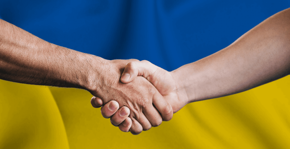 handshake in front of a ukrainian flag.