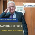 Former GS-Foundation project lead Matthias Seeger smiling and saluting while standing indoors.