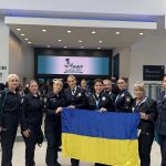 Kateryna Pavlichenko together with Ukrainian police officers holding the national flag in the conference lobby at IAWP Scotland 2025.